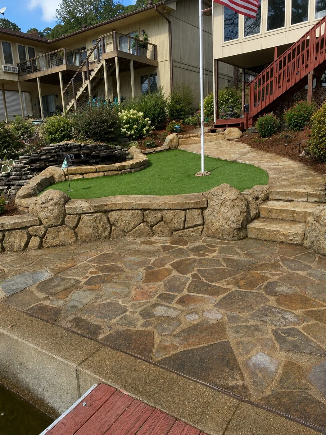 Hand-carved faux-rock concrete retaining wall and decorative stone patio by WeCare Landscapes — a real Central Arkansas lakeside project