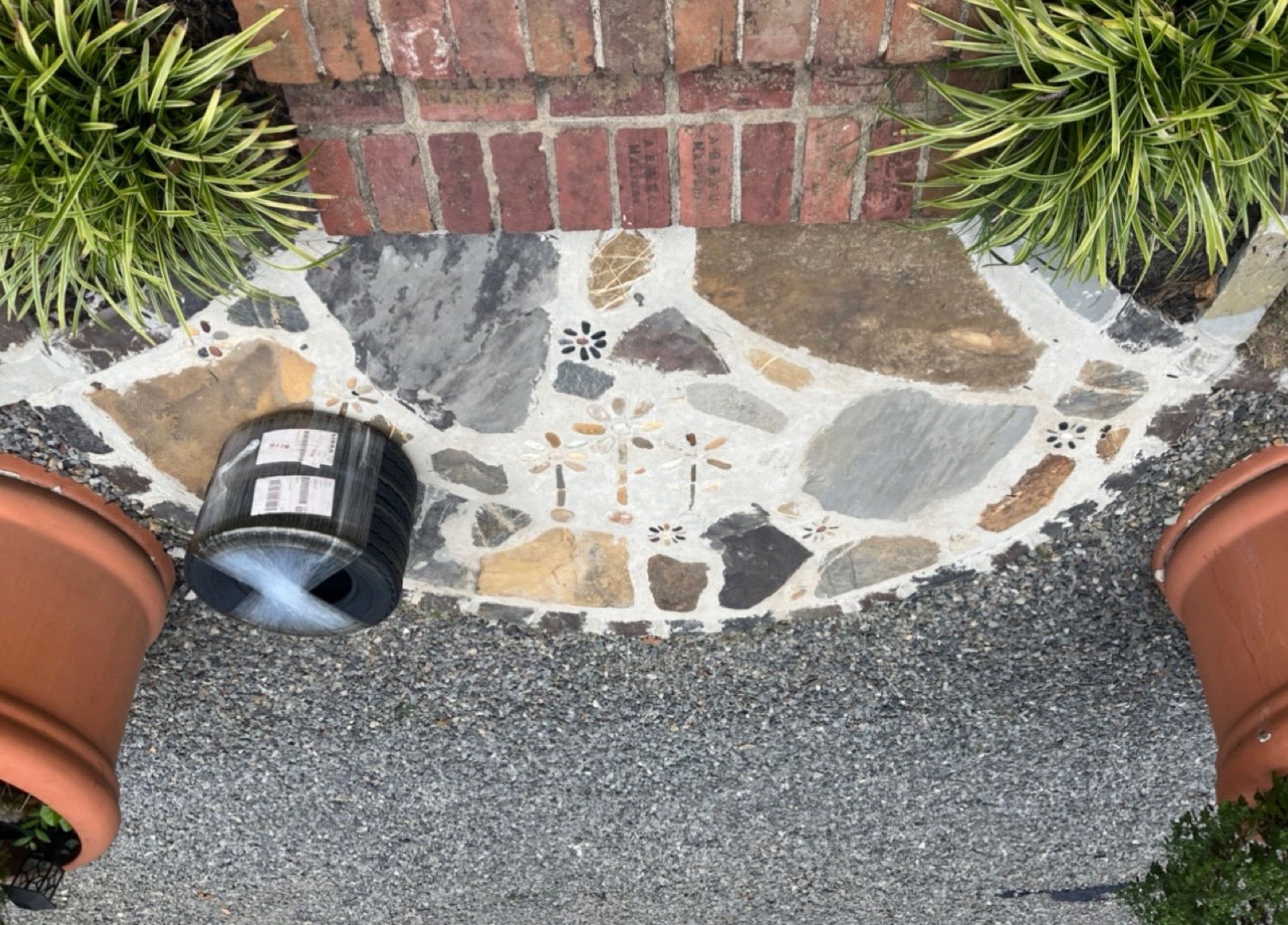 Flagstone patio wrapped around a brick pillar with plantings