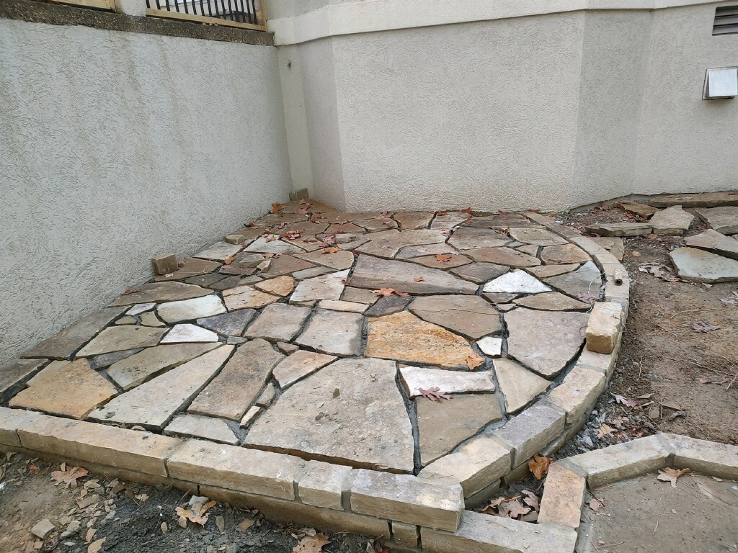 Curved flagstone patio against a stucco courtyard wall