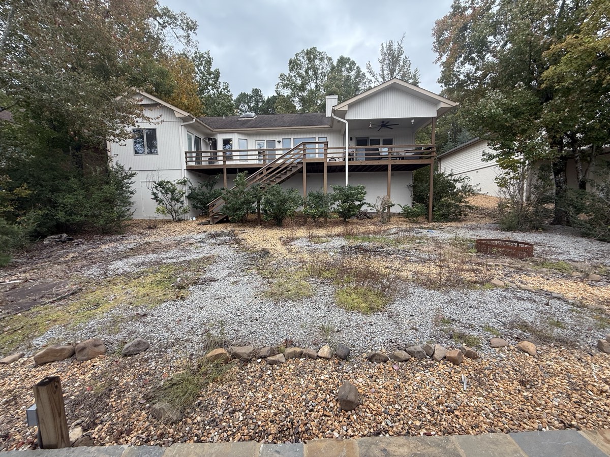 Backyard before β bare gravel and weeds, straight-on view of the deck
