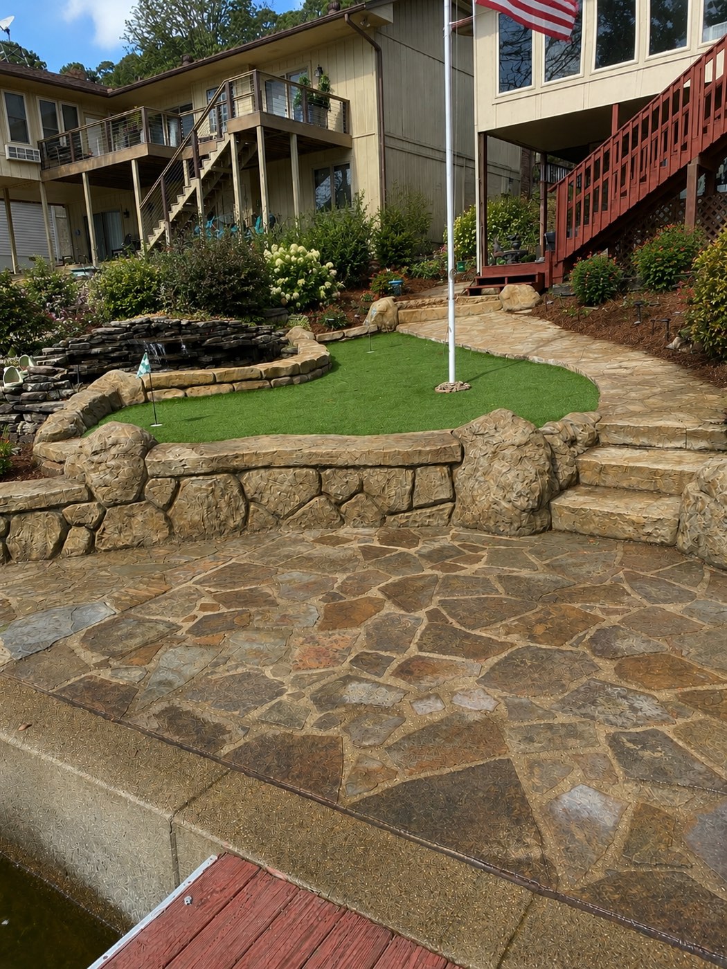 Lakeside stone terraces, flagstone patio, putting green and pondless waterfall after